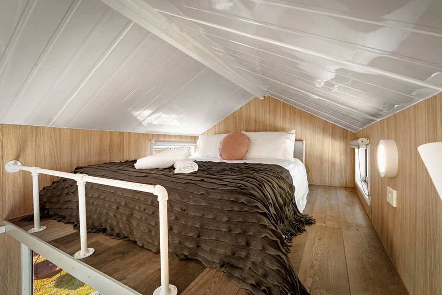 Une chambre à coucher avec un lit, des oreillers, une table de chevet et une fenêtre.