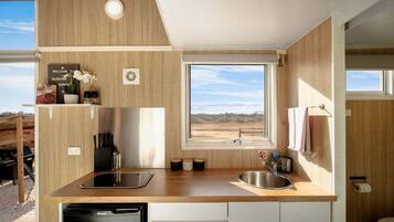 A compact kitchen with a window, built-in appliances, and a view of the outdoors.