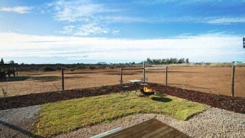 An outdoor area with a fire pit, seating, and a fenced field.