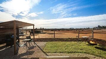 An outdoor patio area with a wooden pergola, seating, and a fire pit.