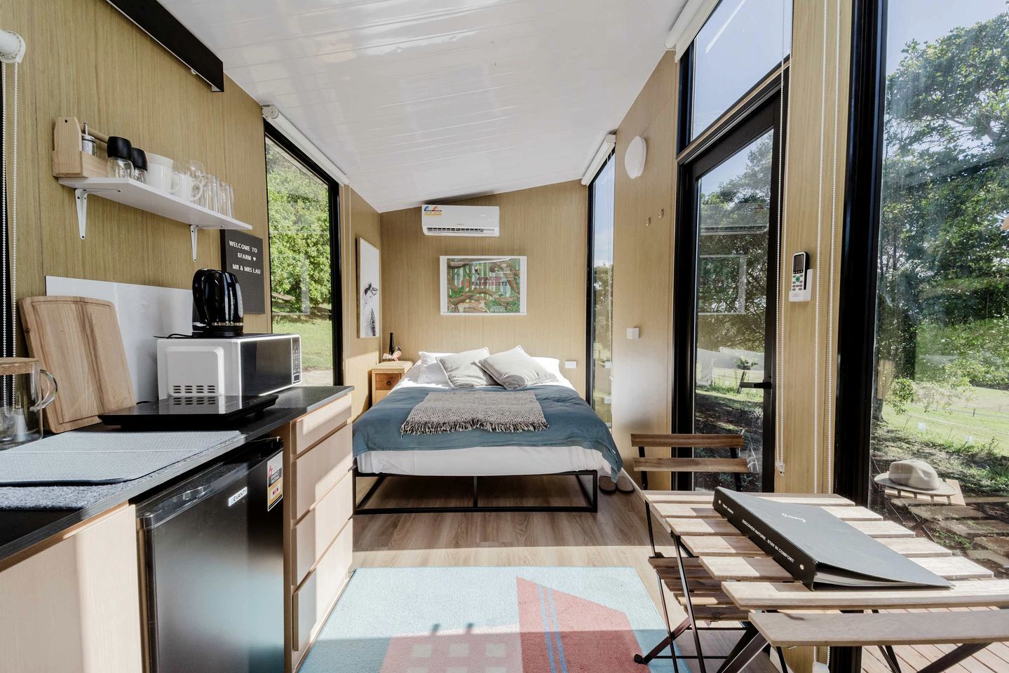Une chambre à coucher moderne avec un lit, une table de chevet et une vue sur l’extérieur.