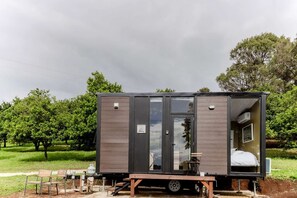 Une structure compacte, composée d’une seule pièce, dotée d’une porte coulissante, d’une petite table et d’un banc à l’extérieur.