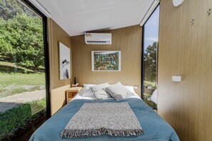 Una camera da letto con un letto grande, un condizionatore d'aria a parete, un quadro e vista sull'esterno.