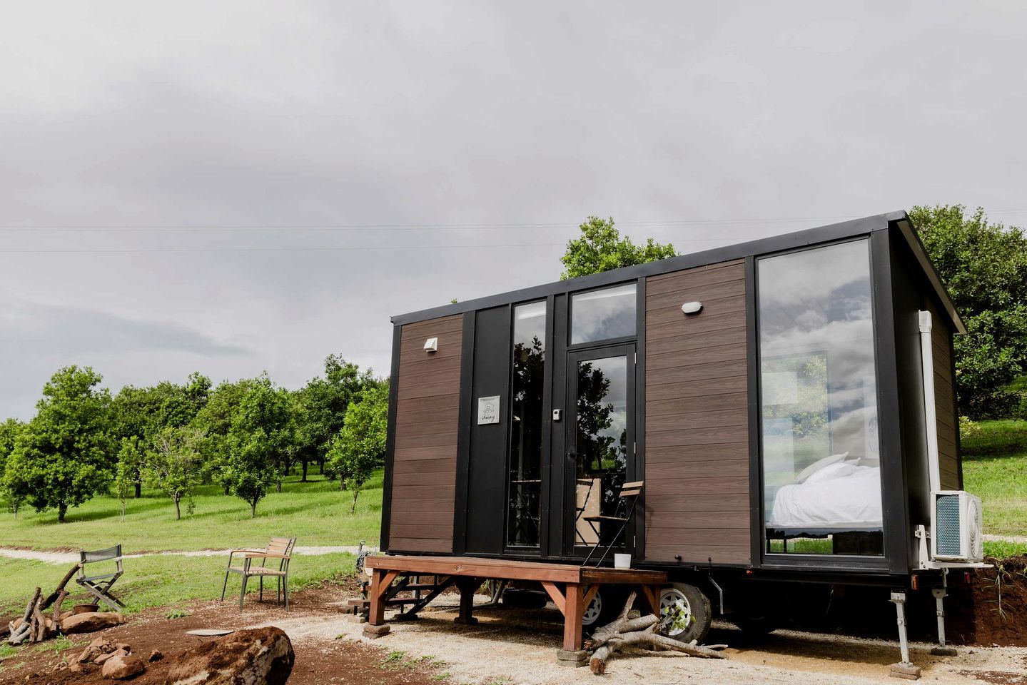 Una cabana moderna i compacta, amb una gran porta de vidre, una panxa a l'exterior i una taula petita.