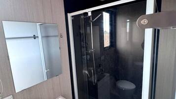 Une salle de bain moderne avec une douche à parois de verre, un lavabo blanc et un miroir.