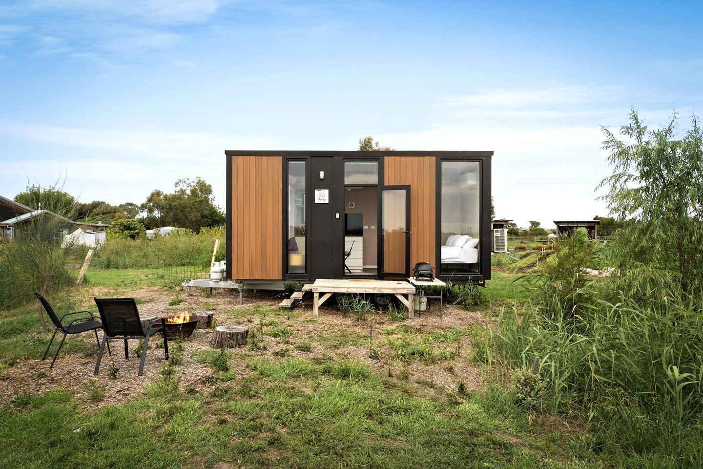 Eine moderne, kompakte Holzhütte mit einer kleinen Terrasse und einem Feuerkorb.
