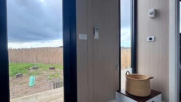 A room with a large sliding glass door leading to a deck, a small wooden bench with a basket, and a grey doormat.