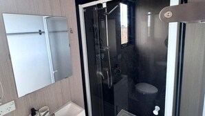 A modern bathroom with a glass-enclosed shower, a white sink, and a mirror. - Farm Stay Tiny House with Nature Escape Views in Boneo, Australia (Boneo)