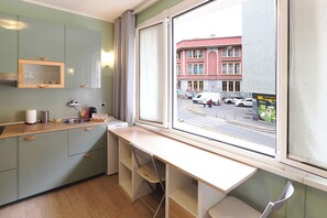 A compact kitchen with a window view of a street scene. - Contempora - Modern Studio Apartment - Chinatown – Arco della Pace (Milano)