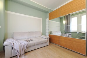 A room with a sofa, a large mirror, and a wardrobe. - Contempora - Modern Studio Apartment - Chinatown – Arco della Pace (Milano)