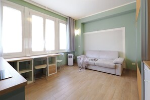 A room with a desk, a chair, a sofa, and a standing heater. - Contempora - Modern Studio Apartment - Chinatown – Arco della Pace (Milano)