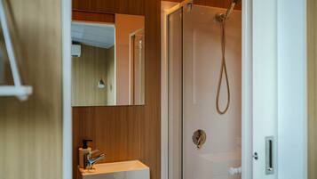 Een badkamer met een douchecabine, een wastafel met spiegel en een deur met handdoekhouder.
