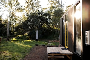 A modern outdoor area with a wooden deck, a bench, and a table.