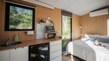 Une chambre à coucher moderne avec un lit, une table de chevet et une vue sur l’extérieur.