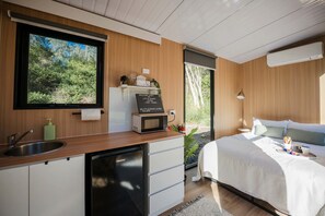 Un dormitorio moderno con una cama, una mesita de noche y vistas al exterior.