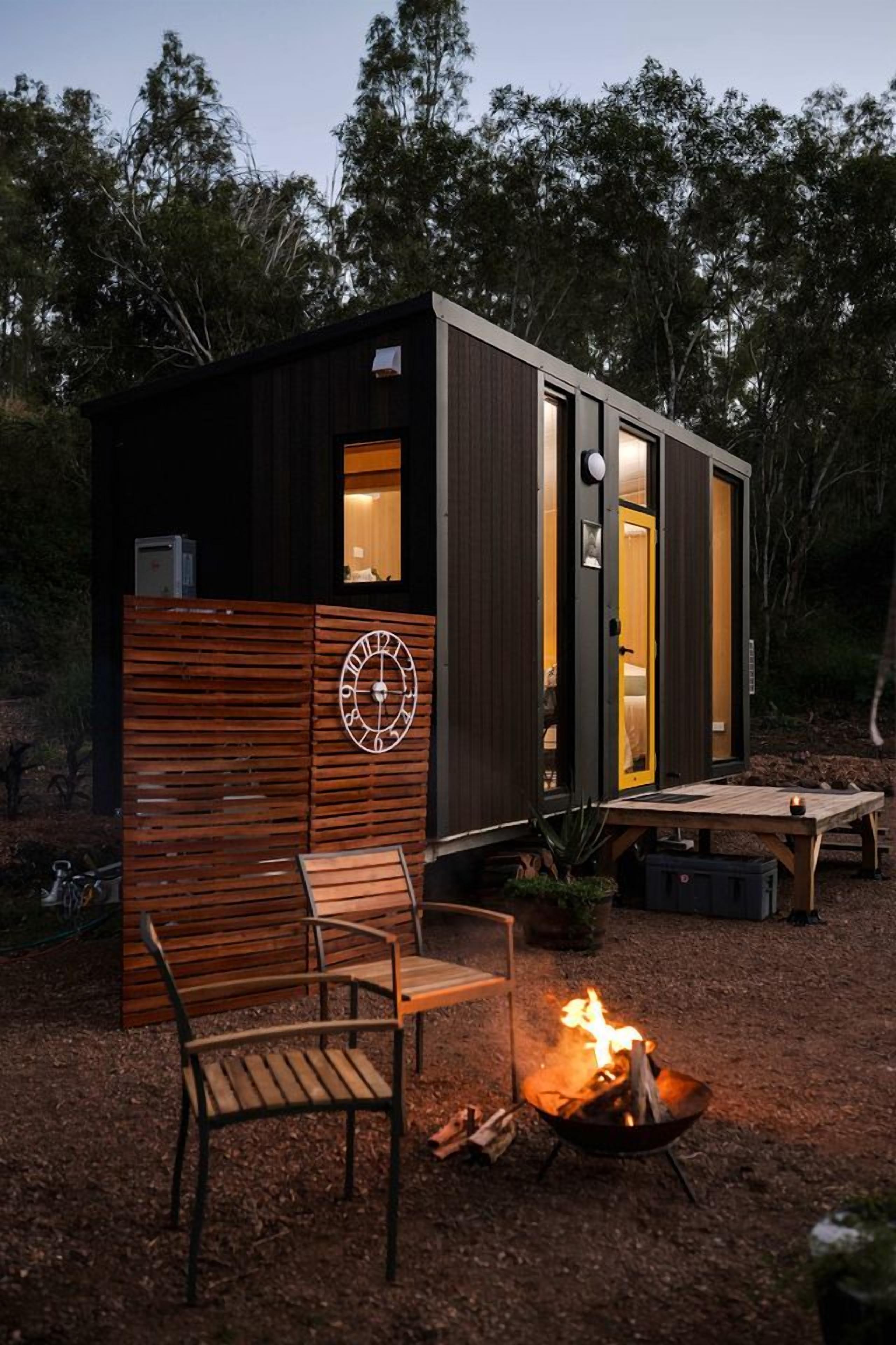 Eine kleine Holzhütte mit Feuerstelle und Bank.