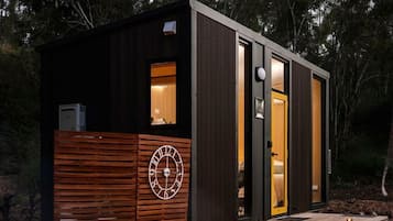 Eine kleine Holzhütte mit Feuerstelle und Bank.
