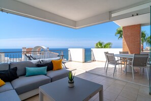 Ein Balkon mit einer Couch, einem kleinen Tisch und Blick auf das Meer.
