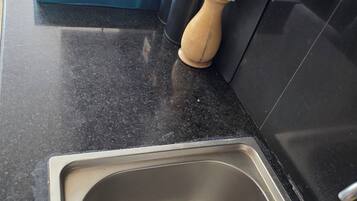 A kitchen with a stainless steel sink, a gas stove, and a decorative vase with white flowers.