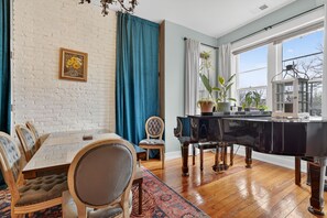 Un coin repas comprenant un piano noir, des chaises en bois, une table et un tapis à motifs.