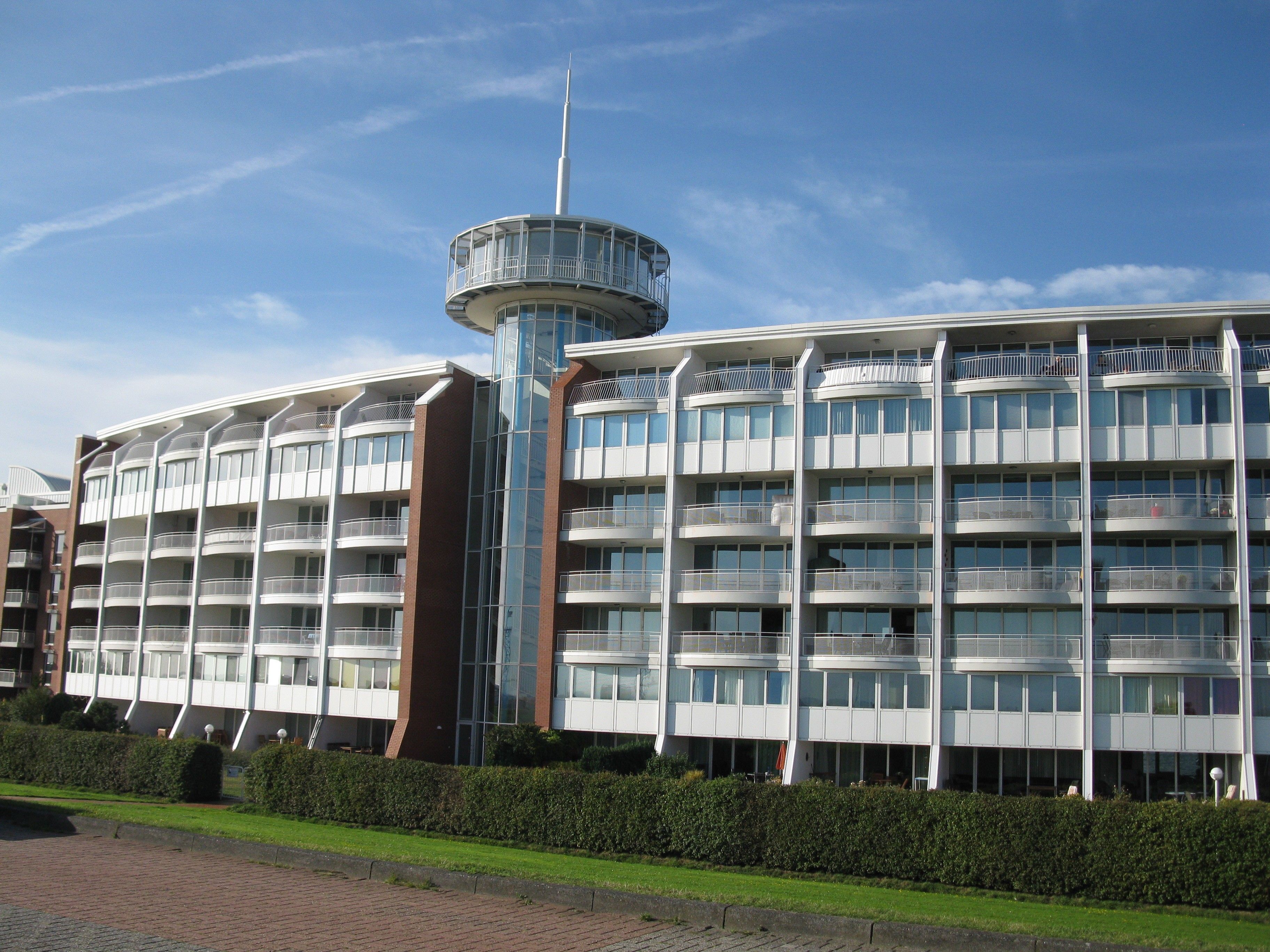 Un hôtel à plusieurs étages, doté d’une tour centrale, de balcons et d’une façade en briques.