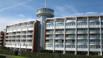 Ein mehrstöckiges Hotel mit einem zentralen Turm, Balkonen und einer Ziegel-Fassade.