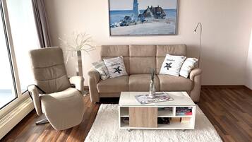 Un salon avec un canapé beige, une table basse blanche et un tableau représentant un phare.