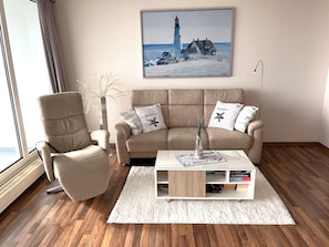 Ein Wohnzimmer mit einem beigen Sofa, einem weißen Couchtisch und einem Gemälde eines Leuchtturms.
