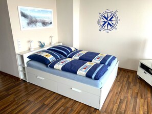 Ein Schlafzimmer mit einem Bett, einem an der Wand befestigten Kompass und einem Gemälde.