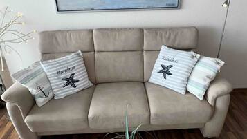 Un sofá color beige con dos almohadones, uno con un diseño de estrella de mar y el otro con la palabra 'Meereslust'.