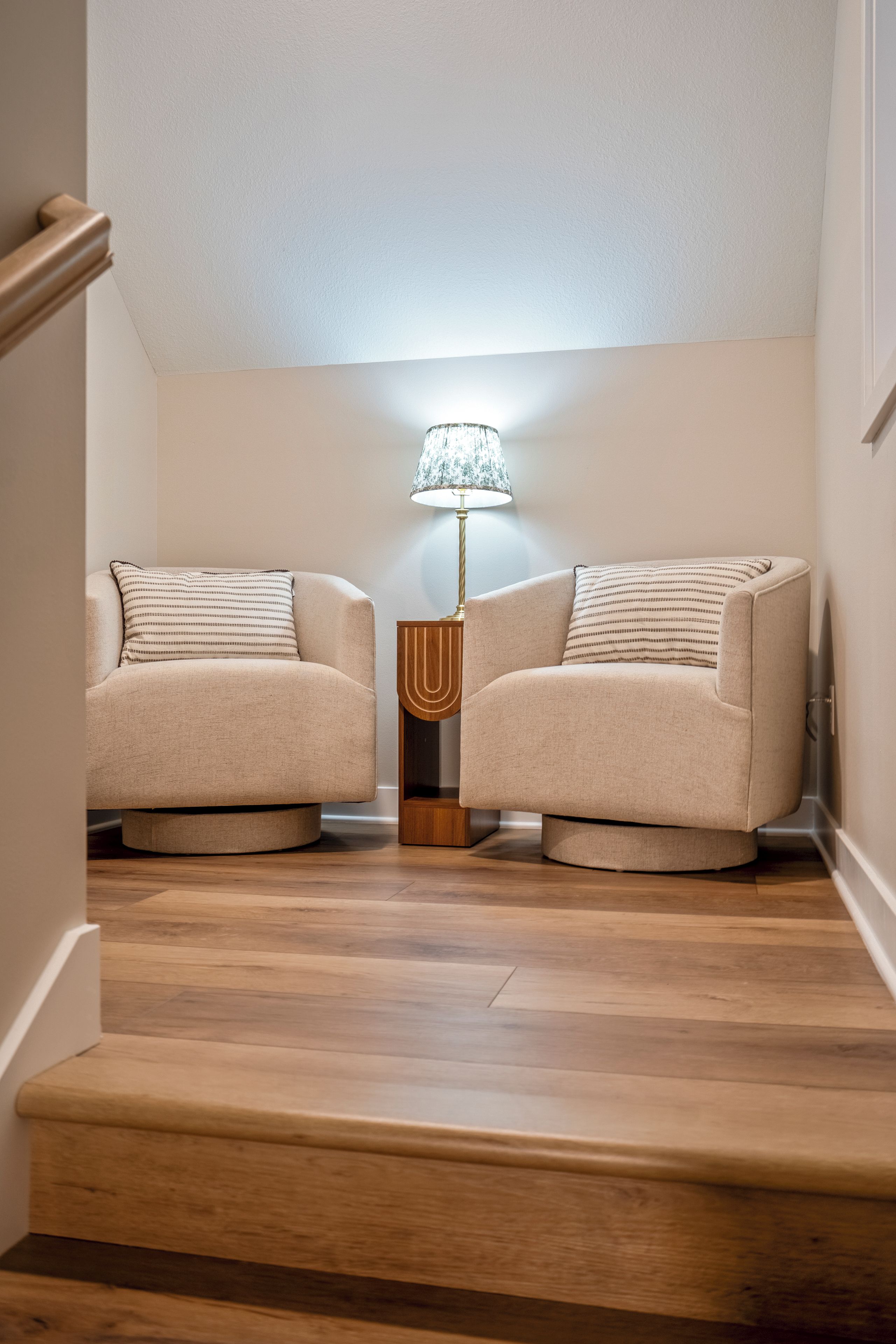 A staircase leading to a living area with two armchairs and a lamp.