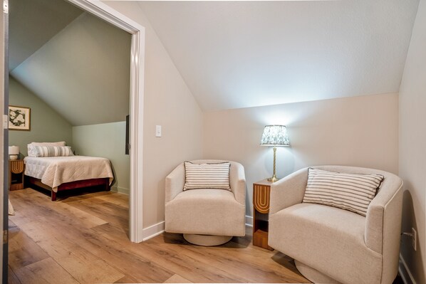A bedroom with a bed, a nightstand, a lamp, and a chair.