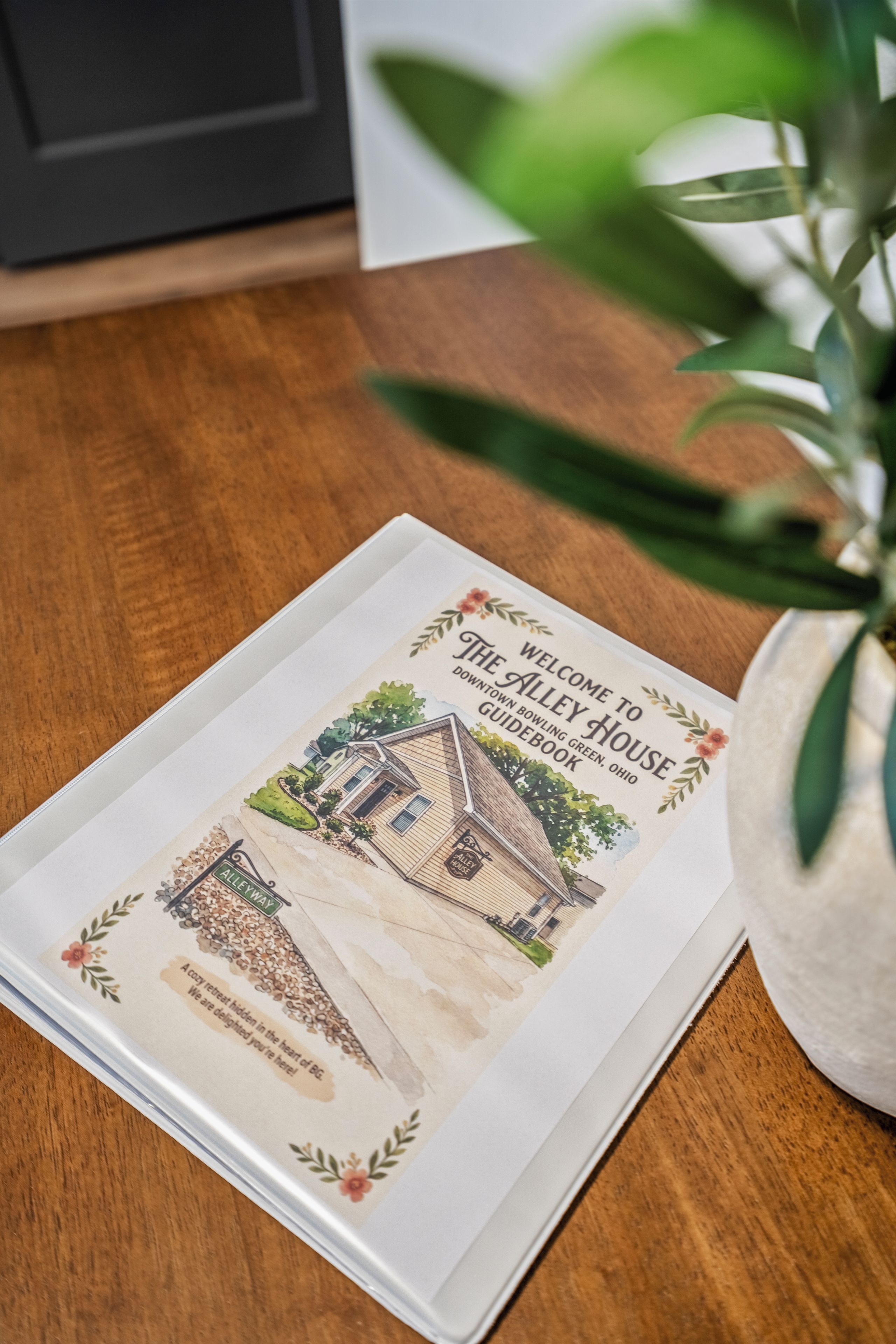 Un folleto de bienvenida del The Alley House en Green, Ohio, con una ilustración de la casa y una vista de la calle.