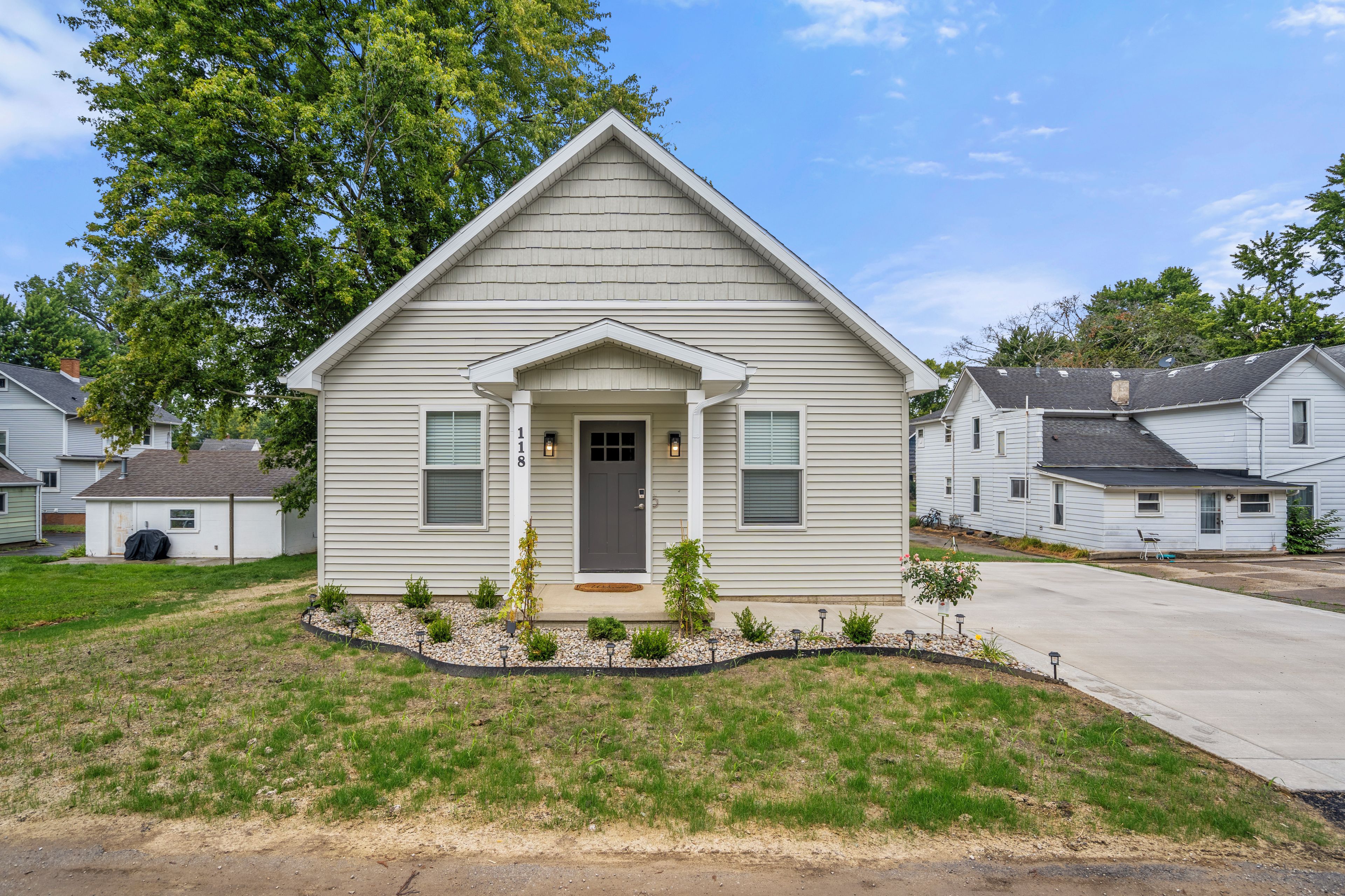 A single-story house with a front porch, a small garden, and a driveway.