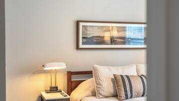 Una camera da letto con un letto, un comodino con una lampada, un quadro appeso al muro e una finestra.