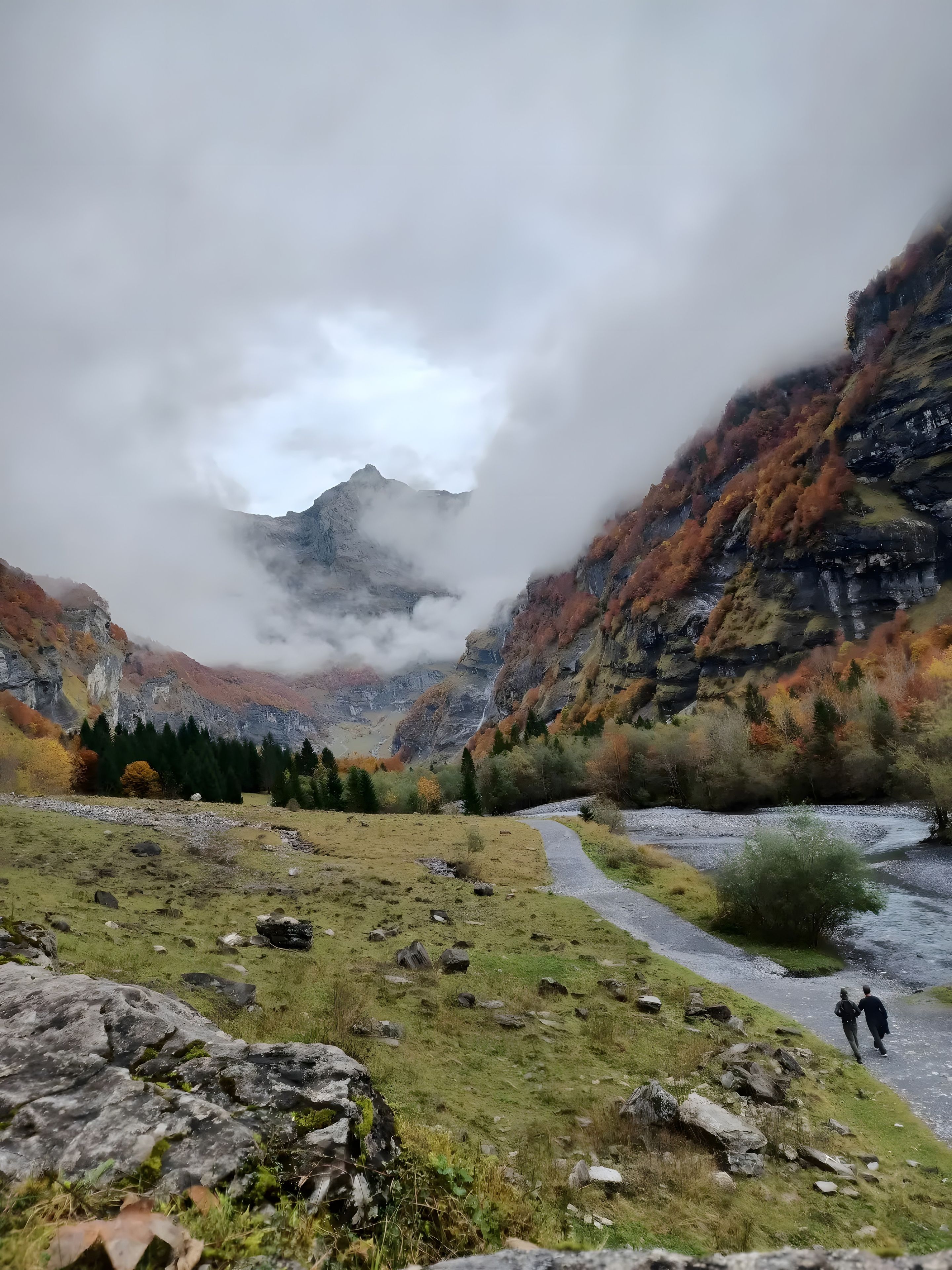 Un paysage montagneux avec une rivière, un terrain rocheux et un sentier.