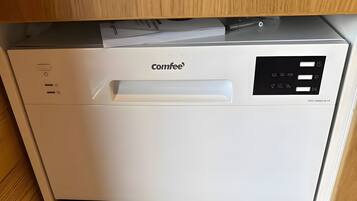 Eine kompakte, weiße Kaffeemaschine mit Bedienfeld und einem einzelnen Hebel, auf einem Holzkabinett platziert.