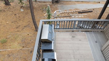 A wooden deck with a grill and a small tree.