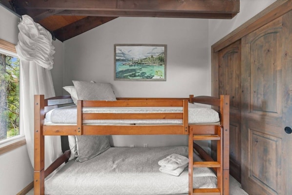 Una cama litera con cabecera, almohadas y una toalla doblada.