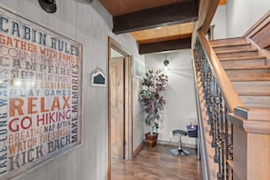Un pasillo con temática de cabaña, con escalera de madera y un cartel con diversas actividades.
