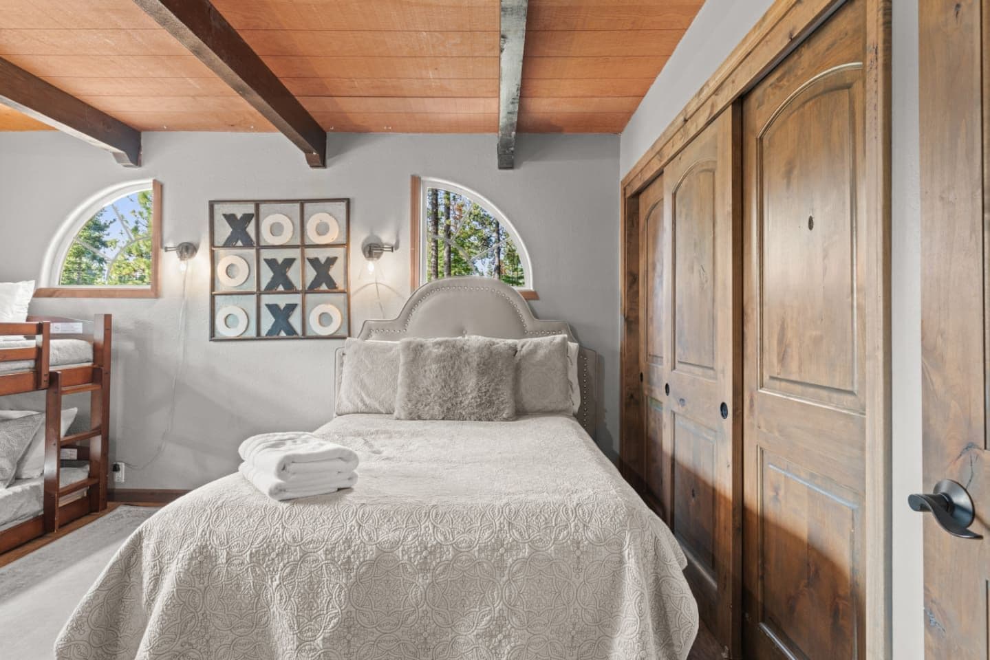 Quarto com cama, guarda-roupa de madeira, janela com vista e parede decorada com quadros.