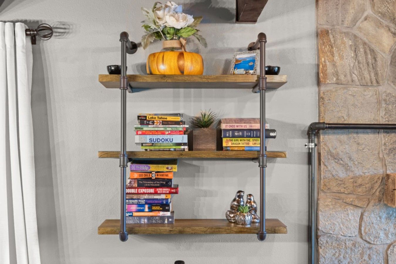 Una mensola a muro in legno con libri, una piccola pianta e oggetti decorativi.