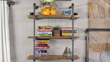 Una mensola a muro in legno con libri, una piccola pianta e oggetti decorativi.