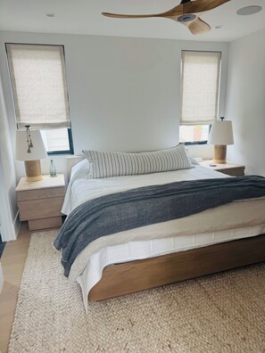 Ein Schlafzimmer mit Bett, Nachttischen, Lampen und einem Deckenventilator.