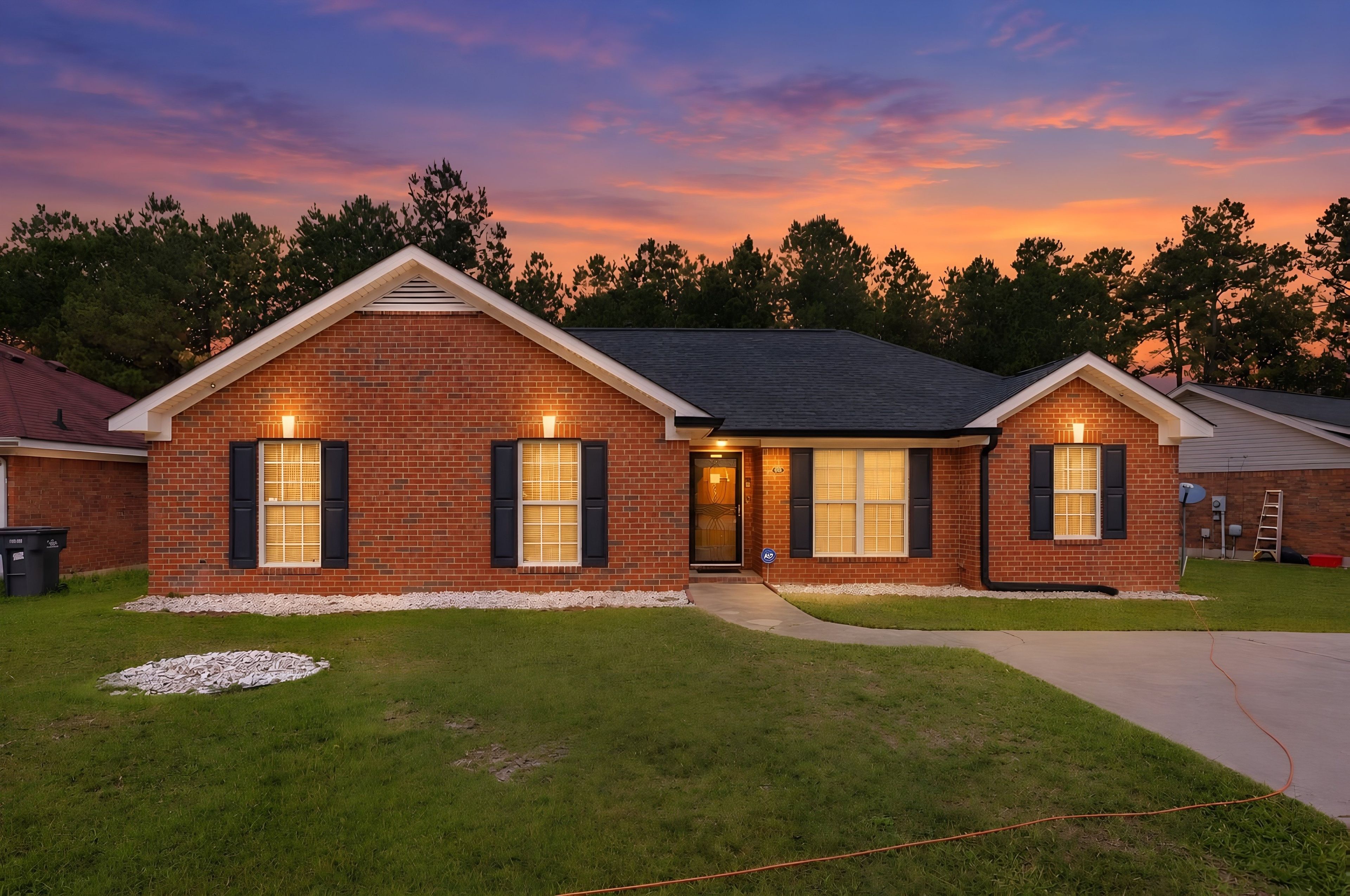 A two-story brick house with a front porch, a driveway, and a well-maintained lawn.