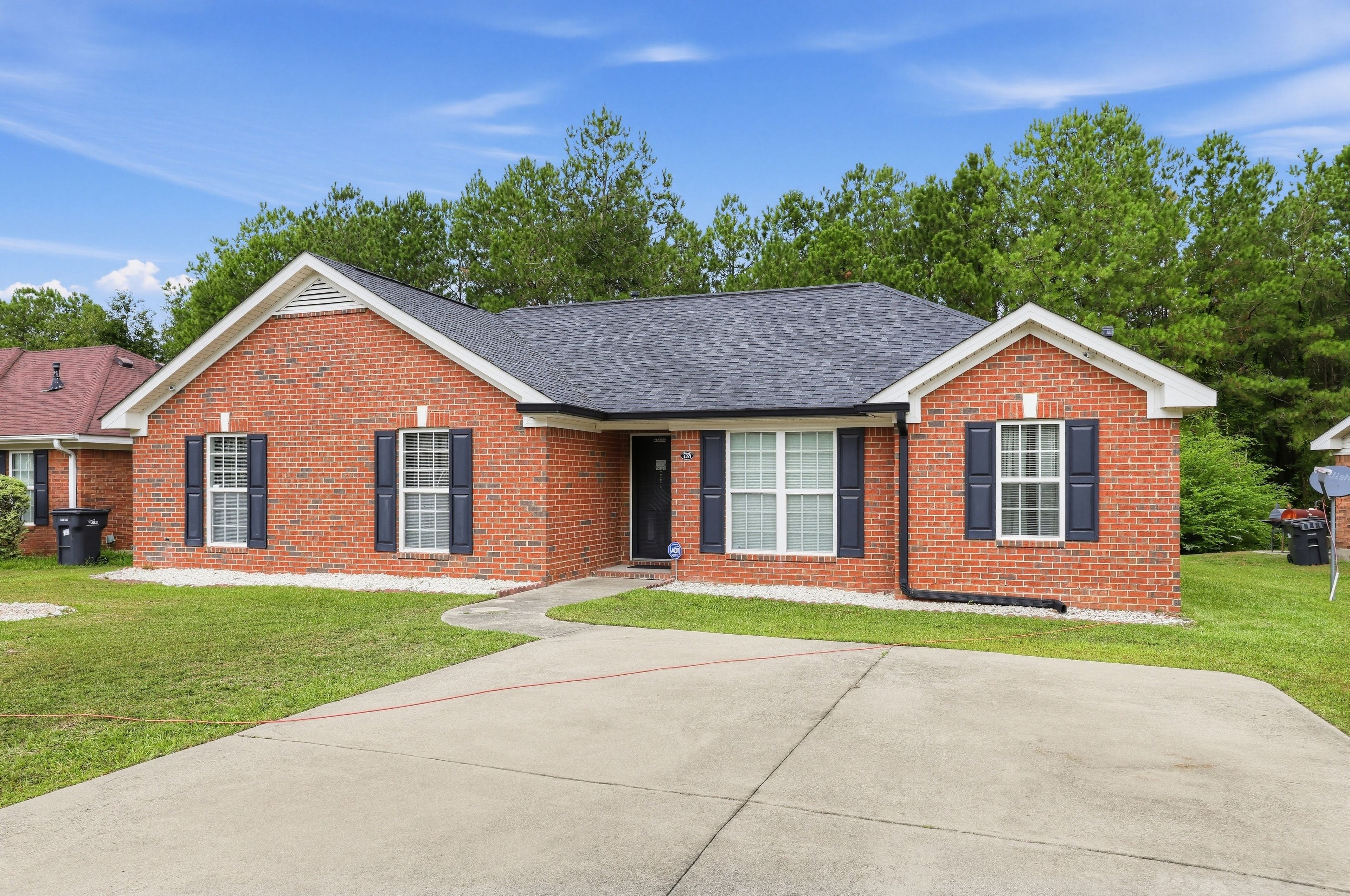 A two-story brick house with a front porch, a garage, and a well-maintained lawn.