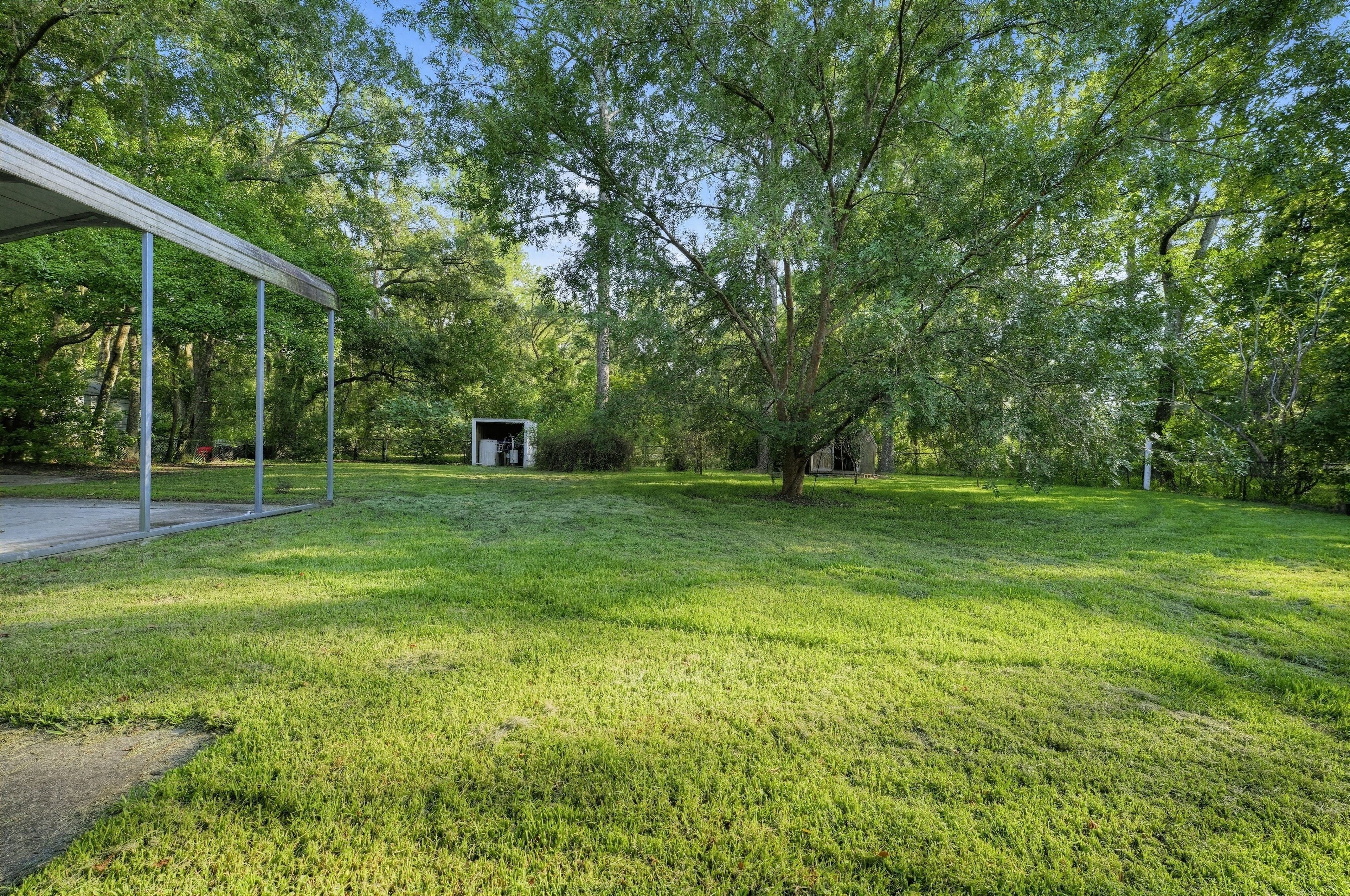 A grassy outdoor area with a covered structure and a small building.