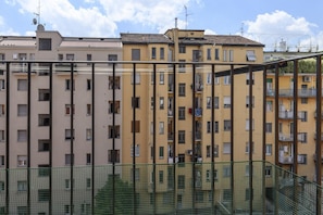 A multi-story residential building with balconies, a green fence in the foreground, and a clear sky. - 10 Via Cadibona – Living Milano (Milan)