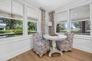A room with a round table and two patterned chairs, large windows with curtains, and a chandelier. - La Laval At Winyah Bay Main And Guest House 8 Bedroom Home (Georgetown)
