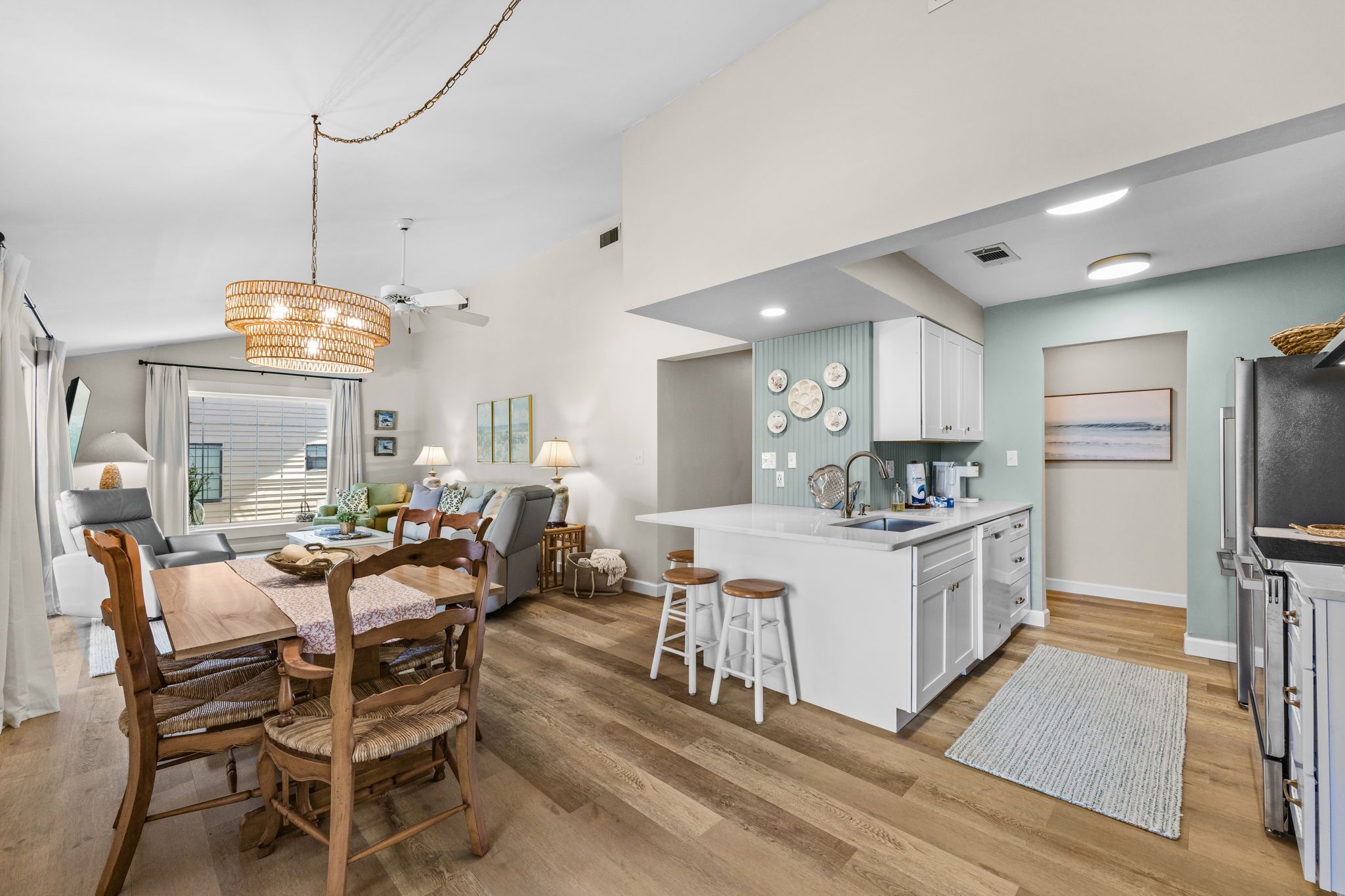 Una cocina amplia con una isla central, una mesa de comedor de madera y taburetes de bar.